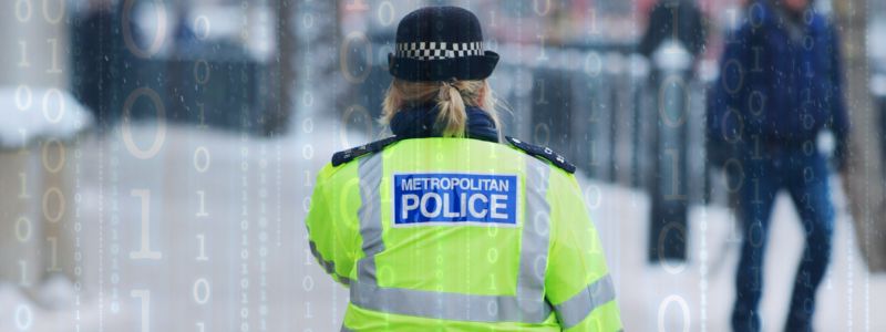 Image of a police officer on her back, walking on the street on a binary code background